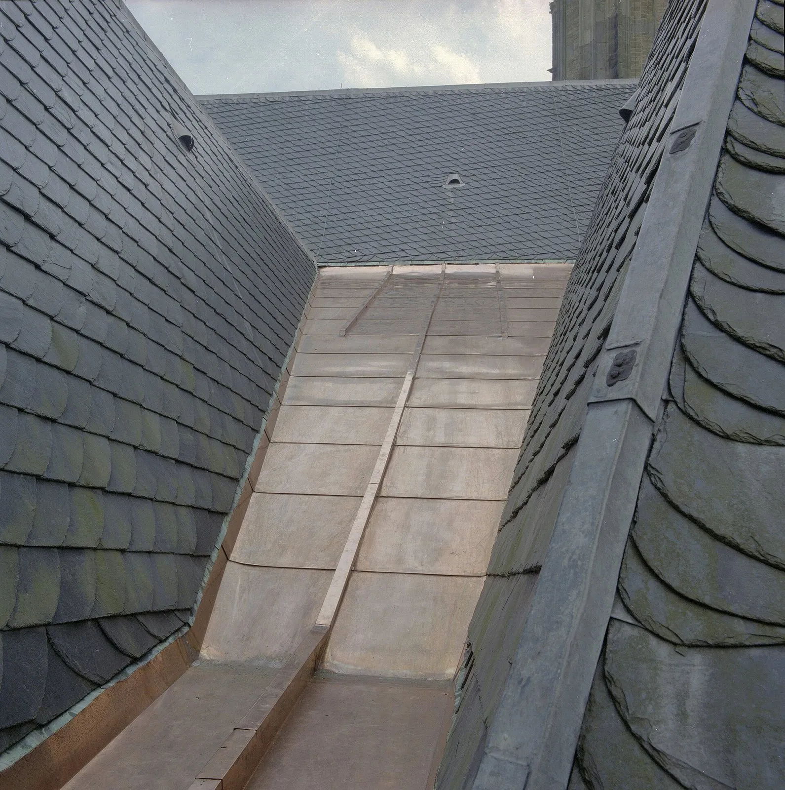 Calha de cobre no encontro entre duas águas de um telhado de ardósia, formando uma água-furtada