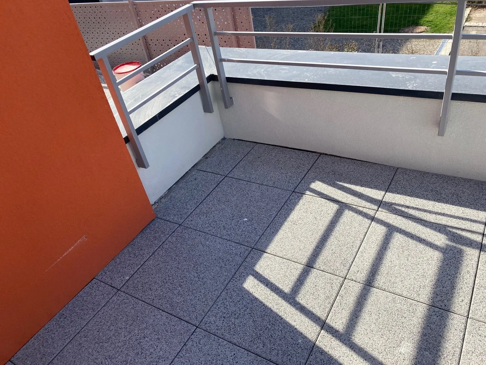 Terraço com piso de placas cinza e mureta perimetral coberta por chapa metálica de acabamento no topo